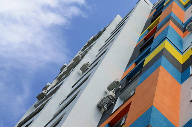 New multy storey residential building and blue sky. Residential houses with many windows and air condition fans